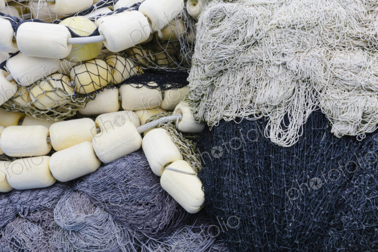 Fishing nets and floats, commercial fishing eqiuipment in a heap on a quayside.
