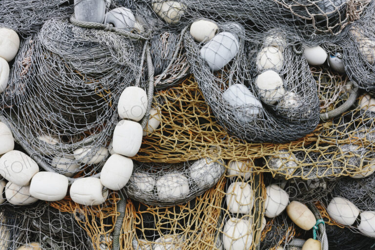 Fishing nets and floats, commercial fishing eqiuipment in a heap on a quayside.