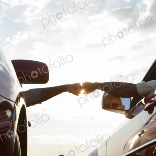 Fist bump between a passenger in one car and driver in another while cars are parked…