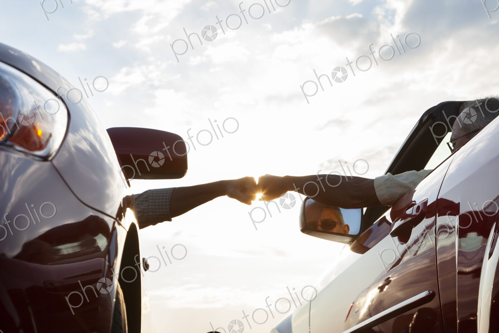 Fist bump between a passenger in one car and driver in another while cars are parked…
