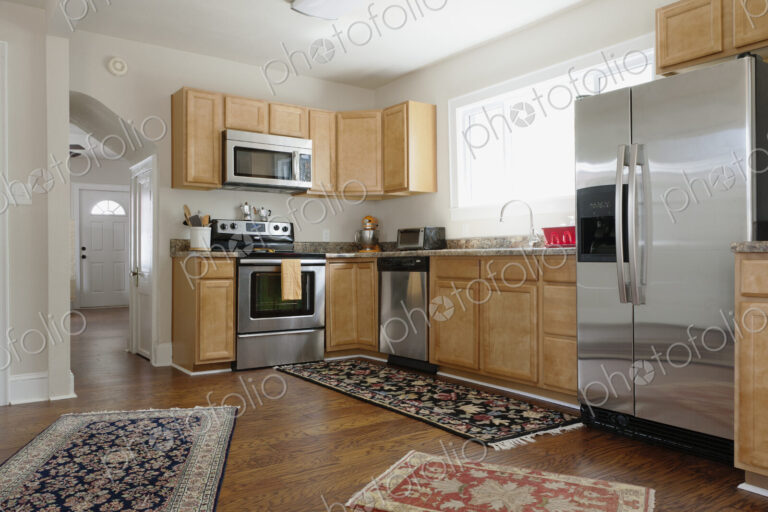 Fitted kitchen in a modern home, ovens and integrated appliances, fridge and rugs on a…