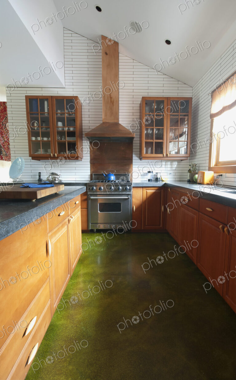 Fitted kitchen units, shelves and sink by the window. A central island with smooth…