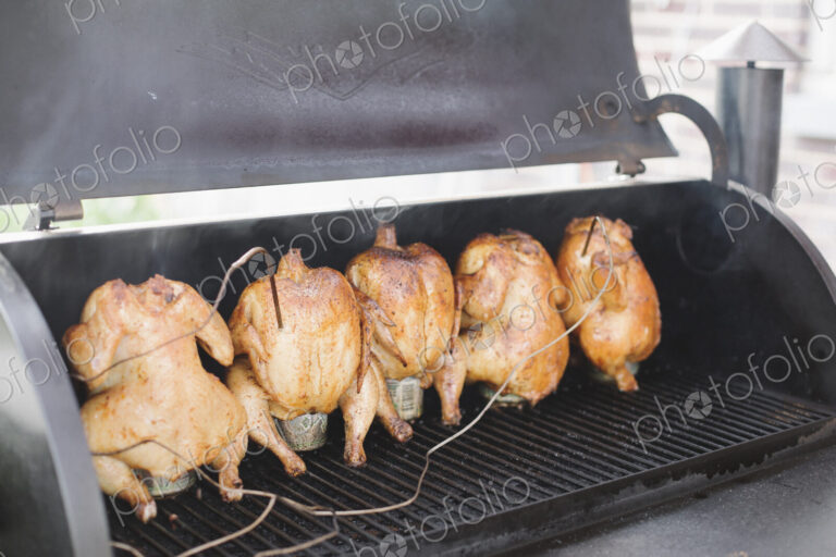 Five whole chickens roasting on a barbecue.