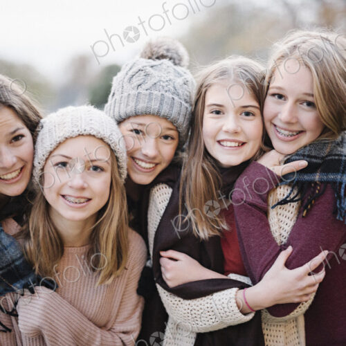 Five young people, girls, friends in warm shawls and woolly hats outdoors. Five young people, girls, friends in warm shawls and woolly hats outdoors.