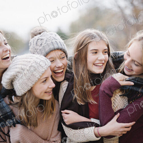 Five young people, girls, friends in warm shawls and woolly hats outdoors. Five young people, girls, friends in warm shawls and woolly hats outdoors.