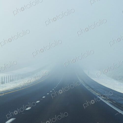 Fog on the highway, a road disappearing into the white mist.