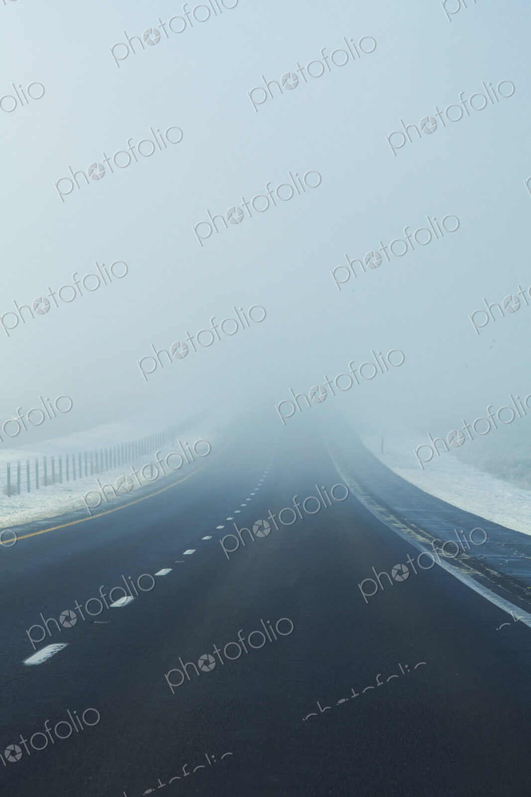 Fog on the highway, a road disappearing into the white mist.