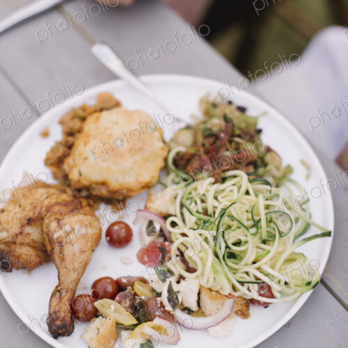 Food on a plate at a garden party, grilled chicken and salad.