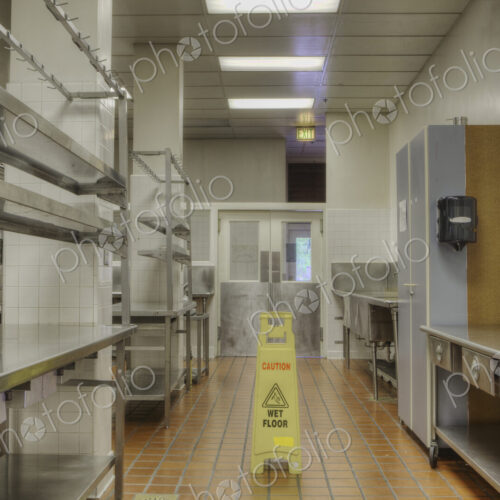 Food preparation area with wet floor sign in large catering kitchen Food preparation area with wet floor sign in large catering kitchen