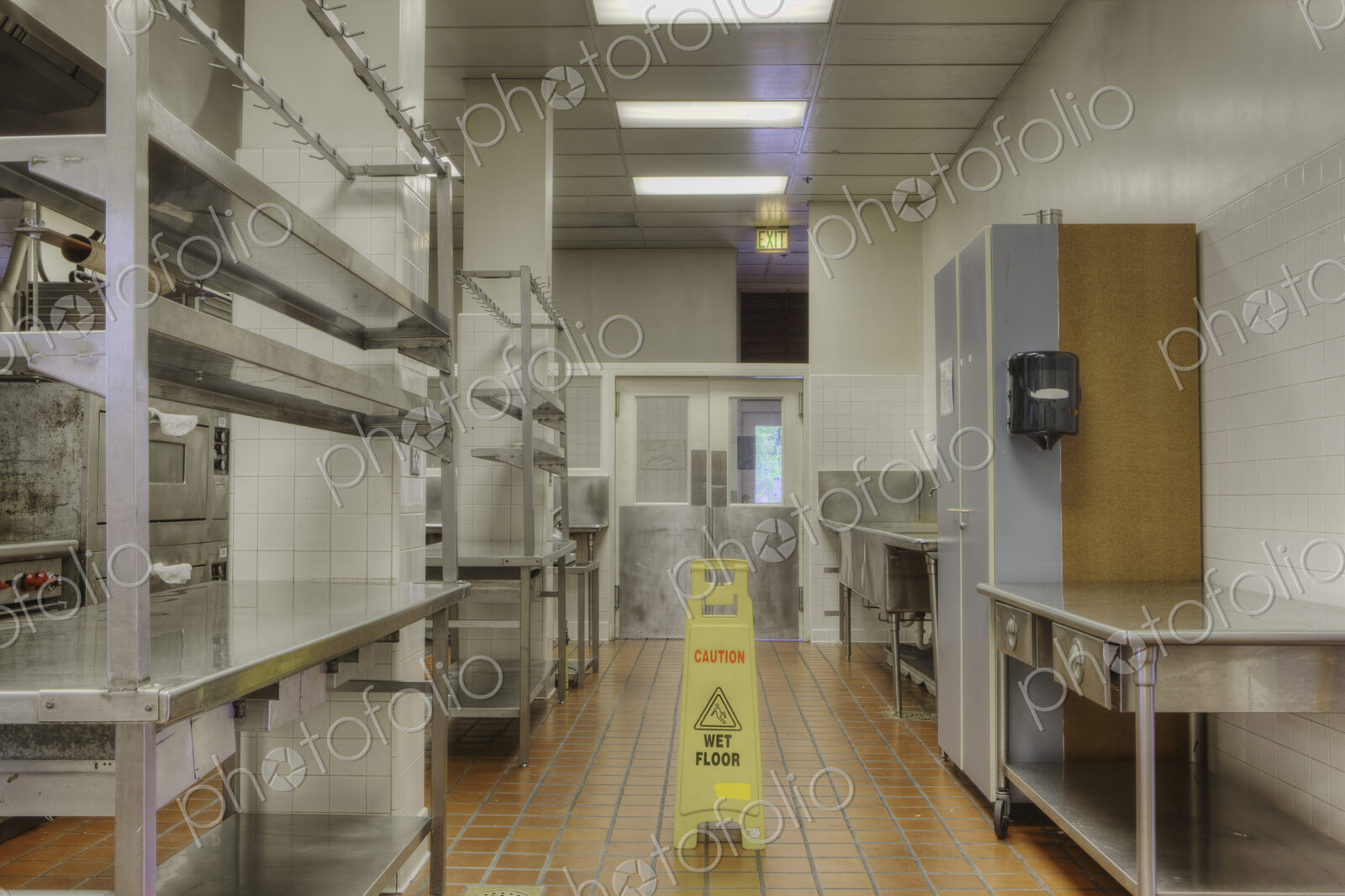 Food preparation area with wet floor sign in large catering kitchen