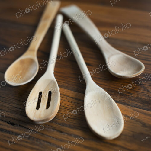 Four bleached wooden spoons, cooking spoons displayed on a wooden tabletop. Four bleached wooden spoons, cooking spoons displayed on a wooden tabletop.