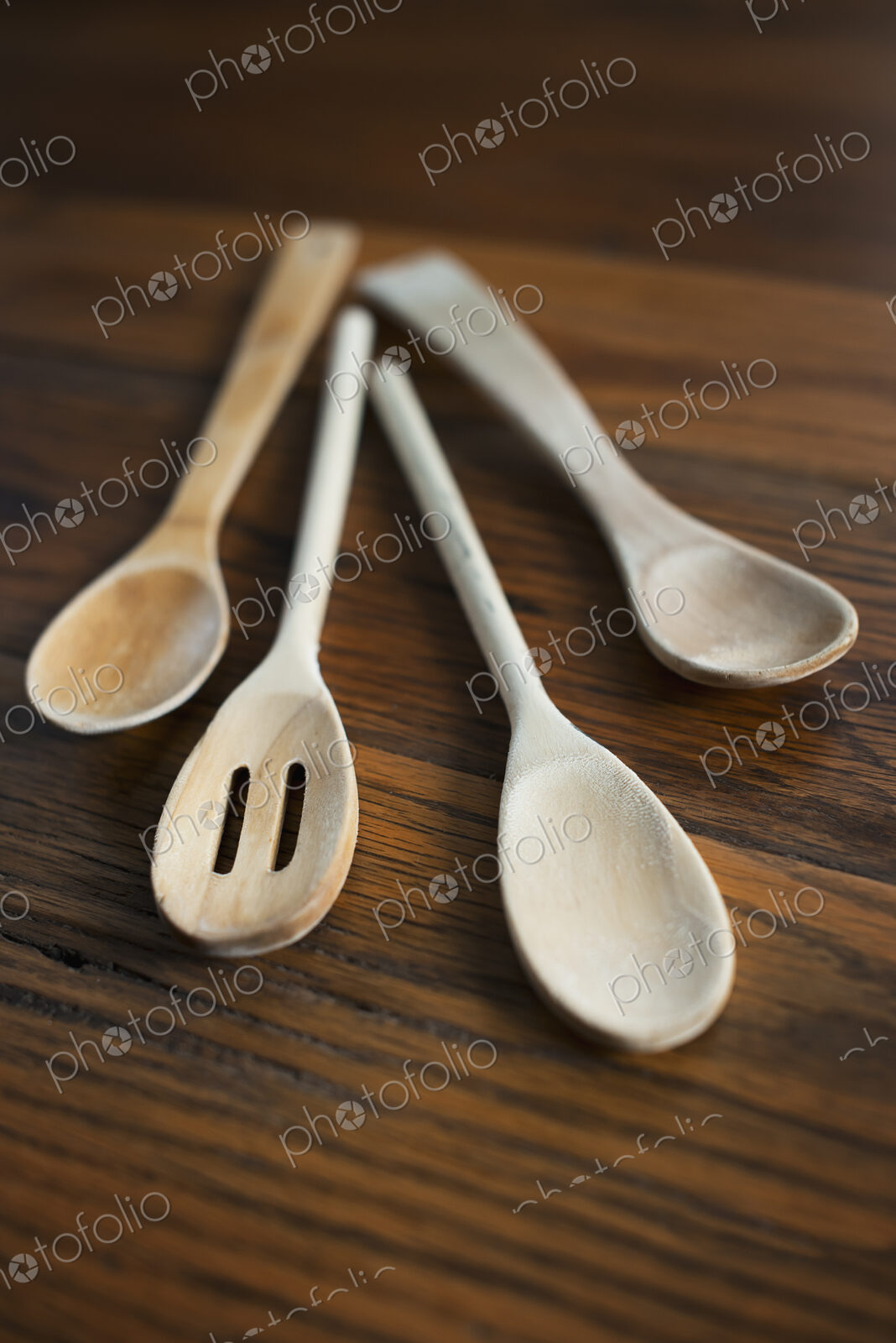 Four bleached wooden spoons, cooking spoons displayed on a wooden tabletop.