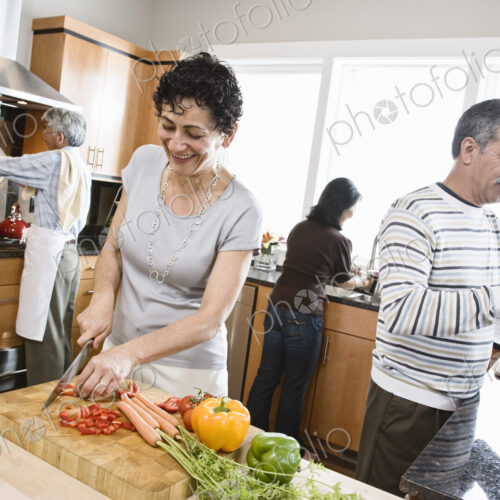Four friends, two couples preparing a healthy meal, chopping vegetables in a kitchen,… Four friends, two couples preparing a healthy meal, chopping vegetables in a kitchen,…