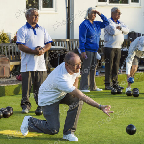 Four people at a lawn bowls match or game. One man kneeling and delivering a bowls… Four people at a lawn bowls match or game. One man kneeling and delivering a bowls…