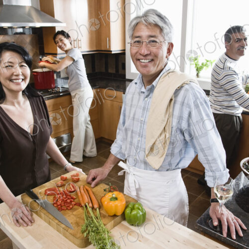 Four people, two couples preparing a healthy meal in a kitchen.