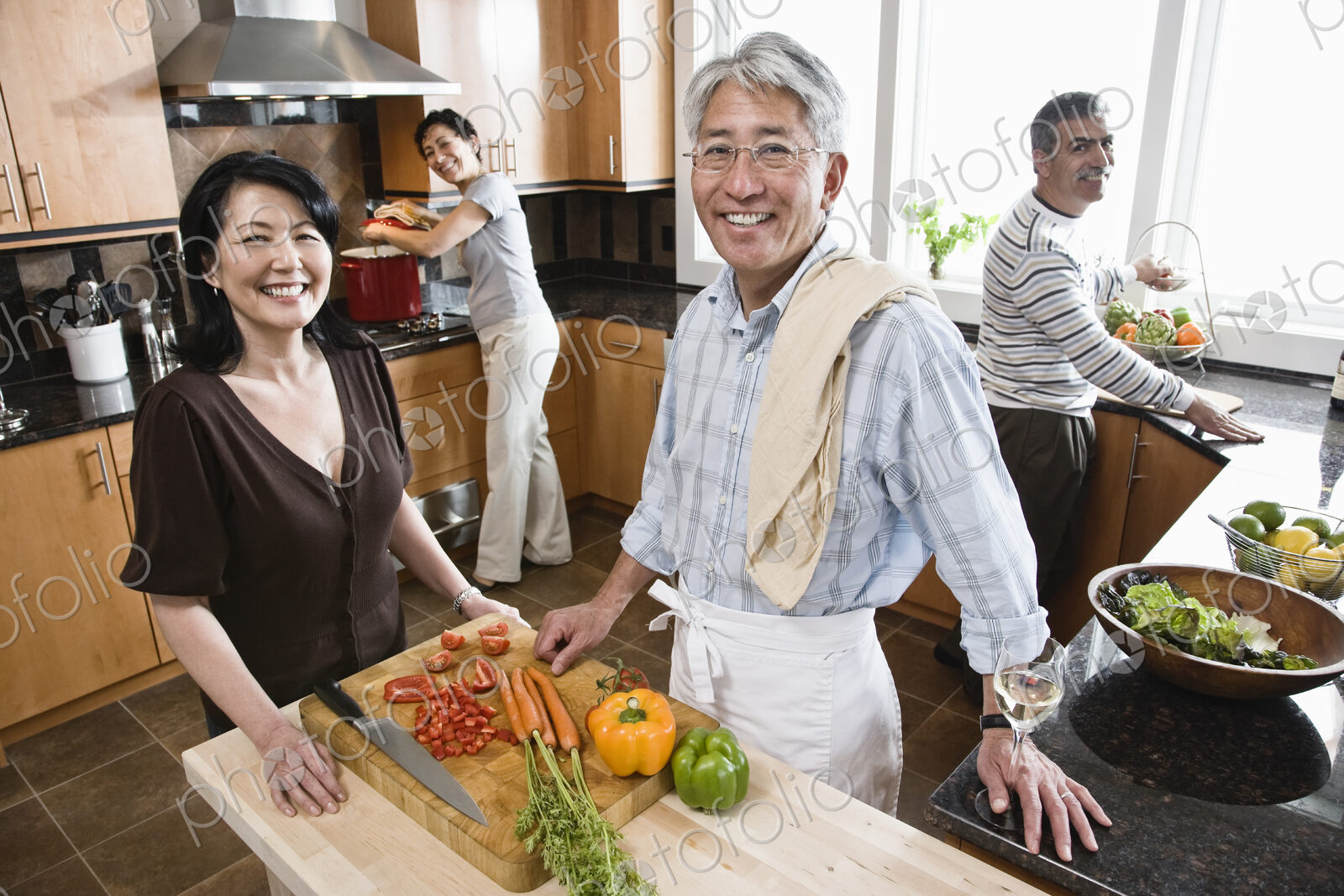 Four people, two couples preparing a healthy meal in a kitchen.