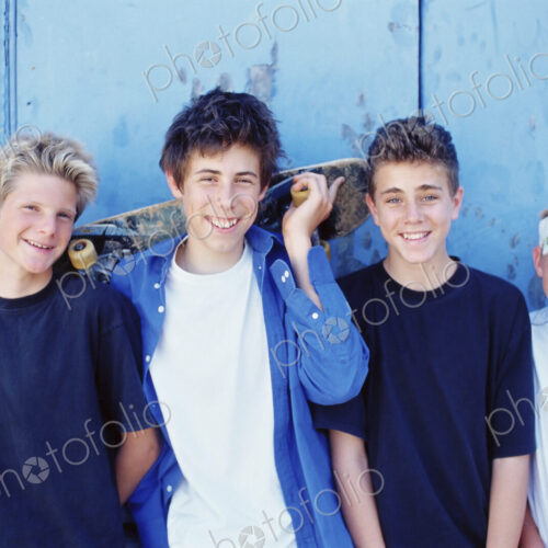 Four young boys in a row, friends skateboarding.