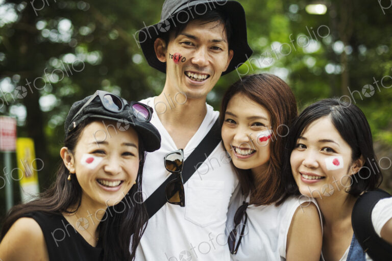 Four young people outdoors, faces painted with Japanese flags