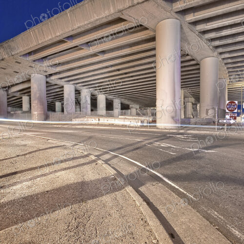 Freeway Overpass Support Structure casting shadows over a road at night. Freeway Overpass Support Structure casting shadows over a road at night.
