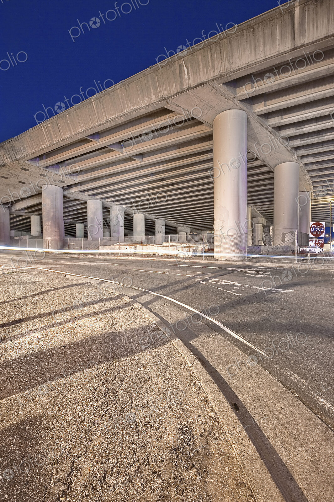 Freeway Overpass Support Structure casting shadows over a road at night.