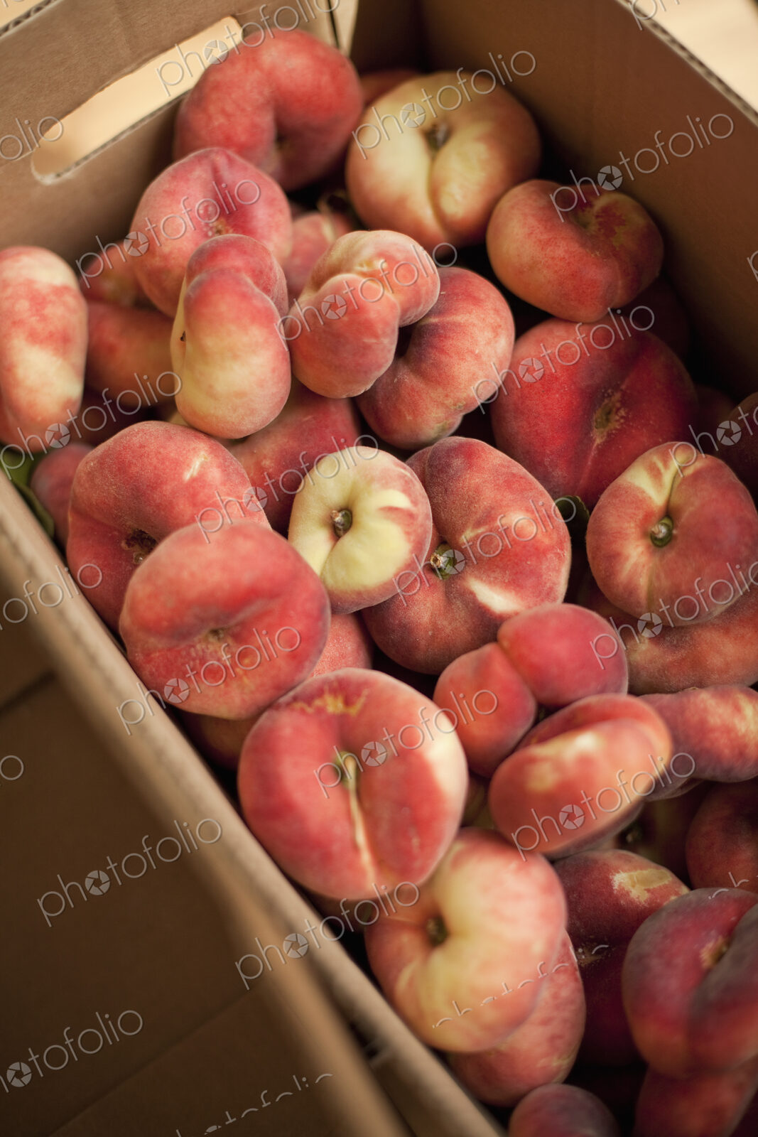 Fresh fruit on an organic farmstand. Doughnut peaches in a box.