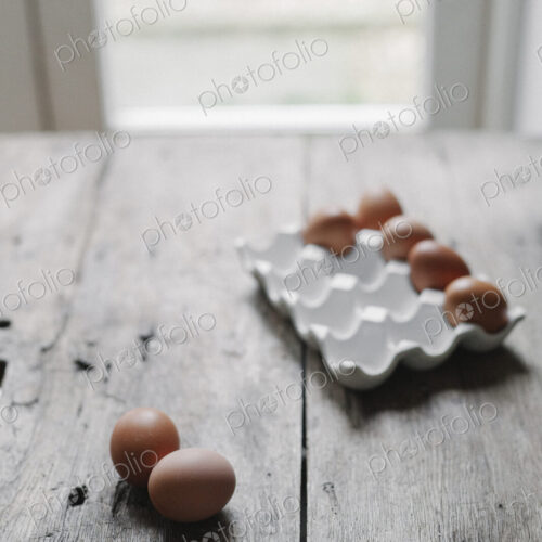 Fresh hen's eggs in a box and on a wooden table. Fresh hen's eggs in a box and on a wooden table.