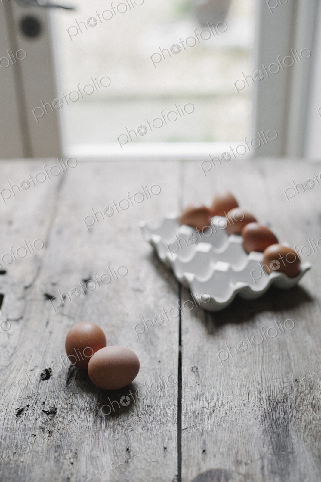 Fresh hen’s eggs in a box and on a wooden table.