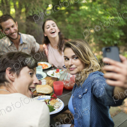 Friends at a woodland picnic, one woman taking a selfy of the group. Friends at a woodland picnic, one woman taking a selfy of the group.