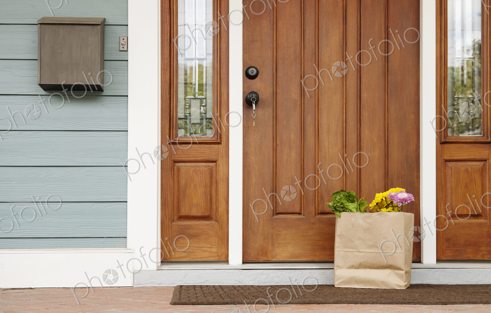 Front door of a house, postbox and a brown bag with flowers and vegetables, Welcome To…