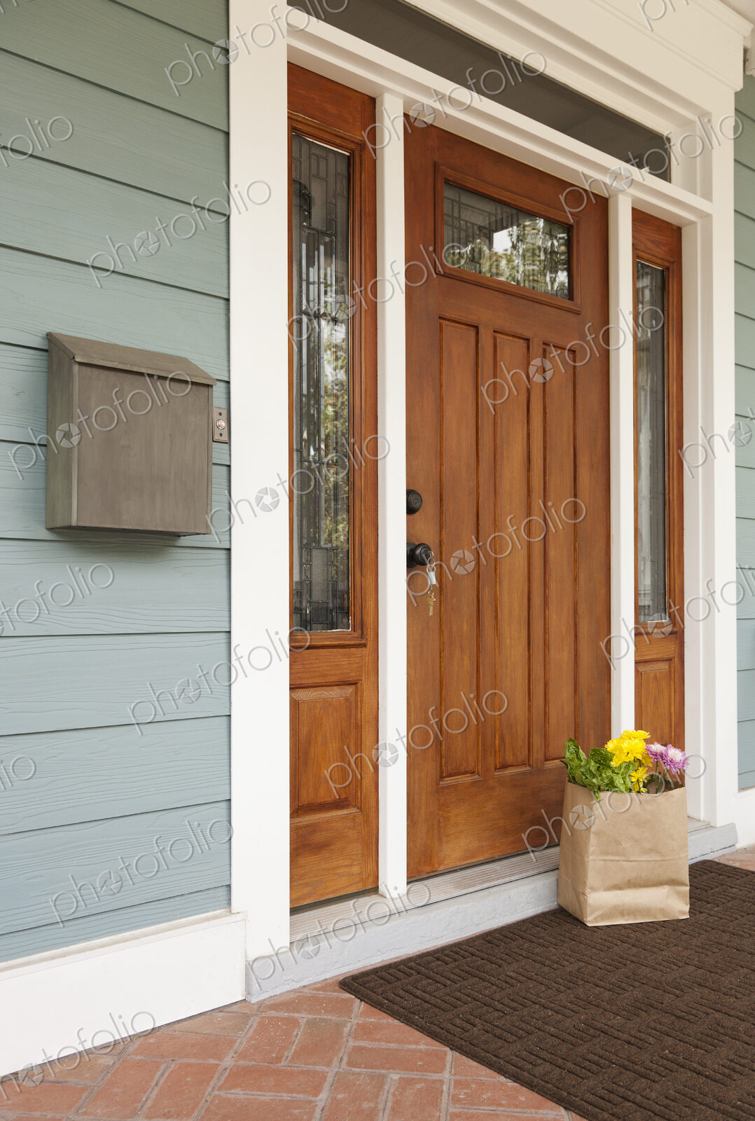Front door of a house, postbox and a brown bag with flowers and vegetables, Welcome To…