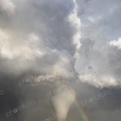 Fully Condensed Tornado with a Rainbow, a spiralling column of air reaching the ground. Fully Condensed Tornado with a Rainbow, a spiralling column of air reaching the ground.