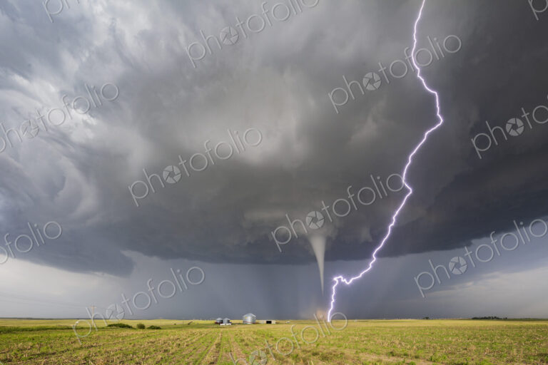 Fully Condensed Tornado with a lightning bolt from the clouds reaching the ground,…