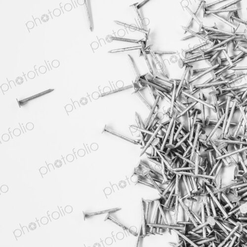Galvanized nails, spread out on a white background.