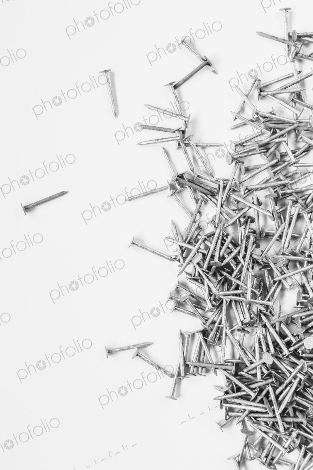 Galvanized nails, spread out on a white background.