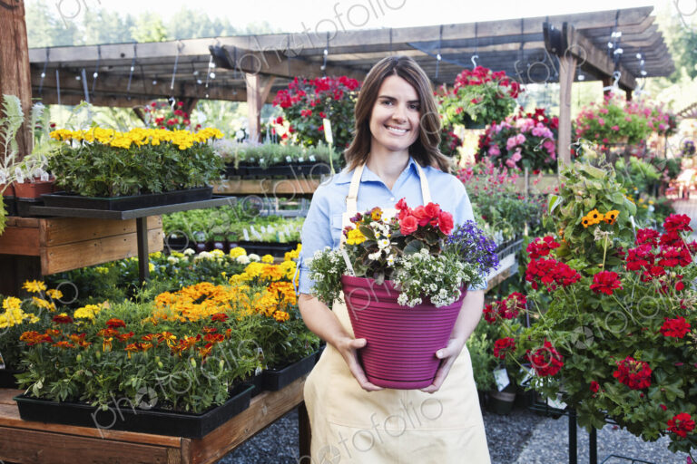 Garden center nursery employee with potted plants.