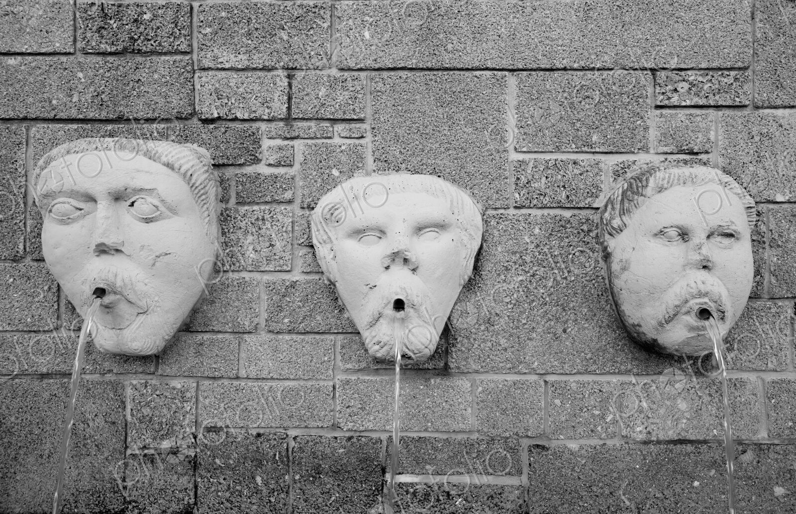 Gargoyle water fountain on stone wall.