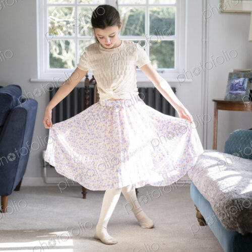 Girl facing camera curtseying in sitting room with head down.