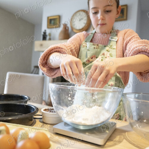 Girl mixing flour in glass bowl in kitchen. Girl mixing flour in glass bowl in kitchen.