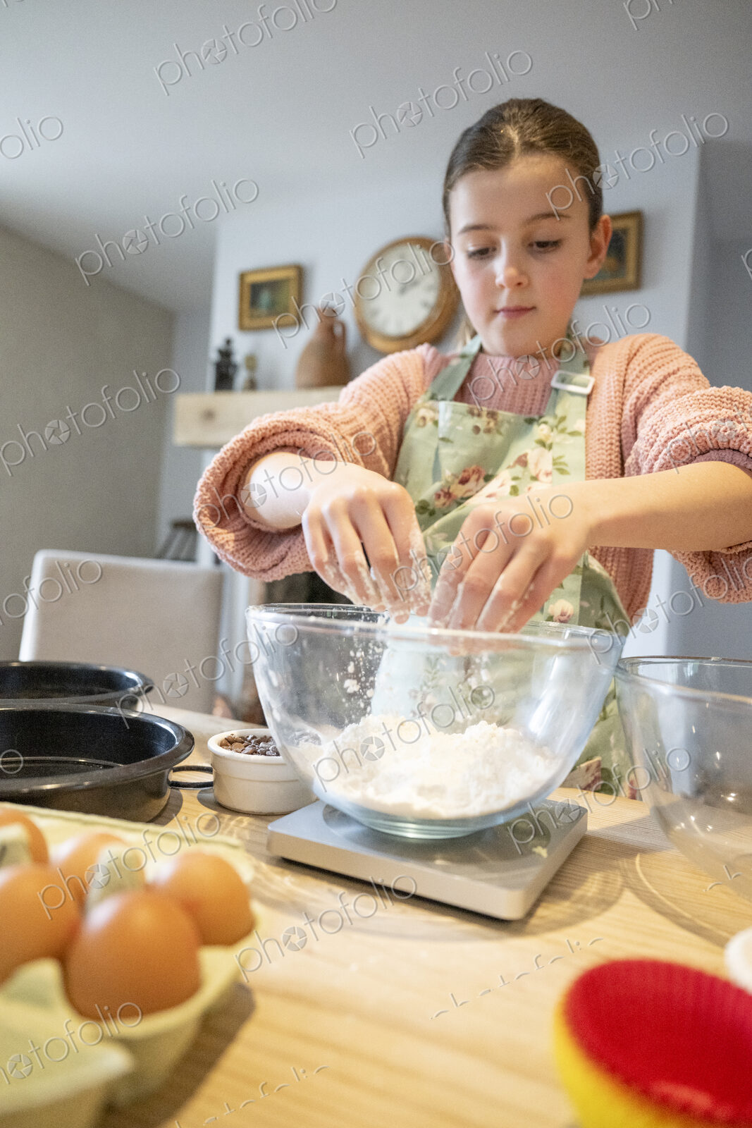 Girl mixing flour in glass bowl in kitchen.