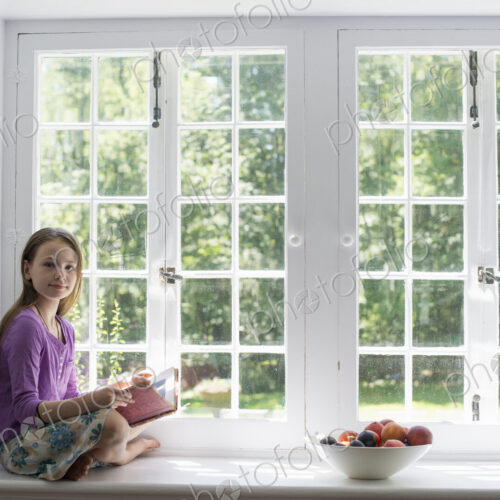 Girl sitting by a window, reading a book. Girl sitting by a window, reading a book.