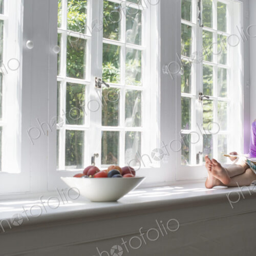 Girl sitting by a window, reading a book. Girl sitting by a window, reading a book.