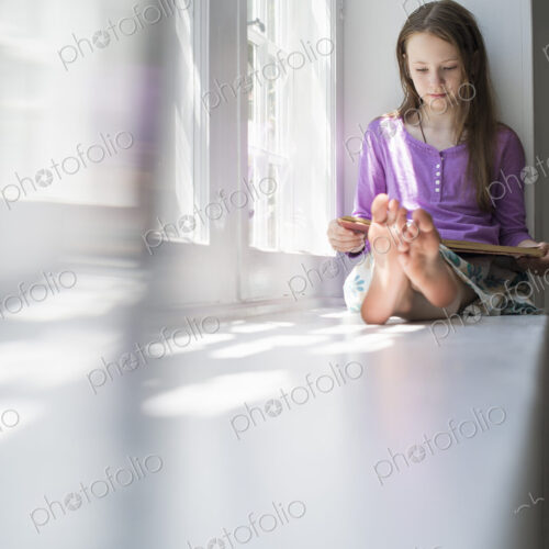 Girl sitting by a window, reading a book. Girl sitting by a window, reading a book.