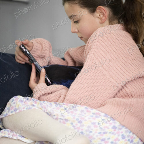 Girl sitting on sofa looking at her smart phone.