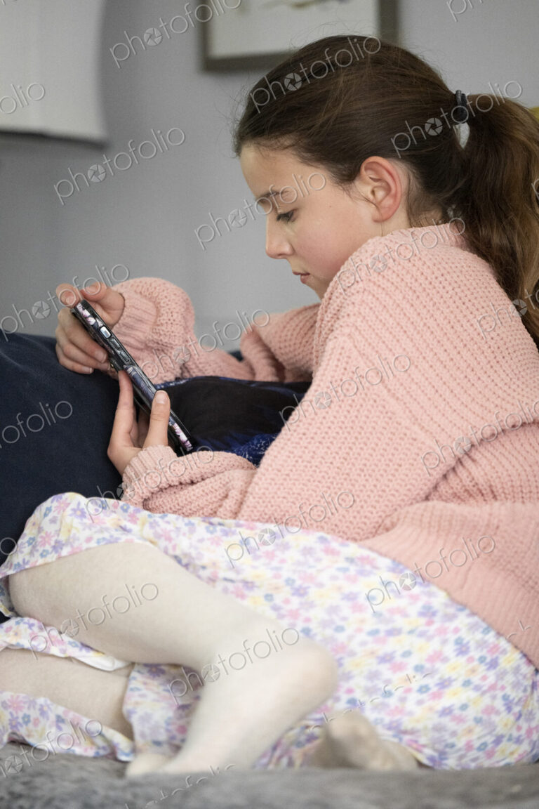 Girl sitting on sofa looking at her smart phone.