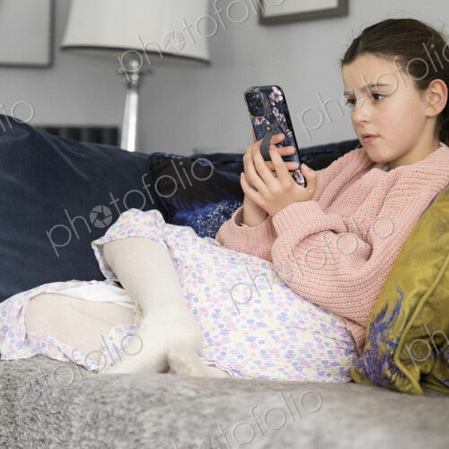 Girl sitting on sofa looking at smart phone.
