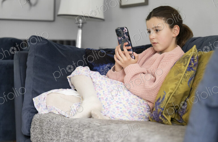 Girl sitting on sofa looking at smart phone.
