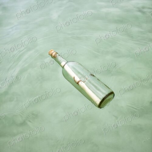 Glass bottle with a rolled note floats on clear Caribbean water. Concept of mystery,… Glass bottle with a rolled note floats on clear Caribbean water. Concept of mystery,…