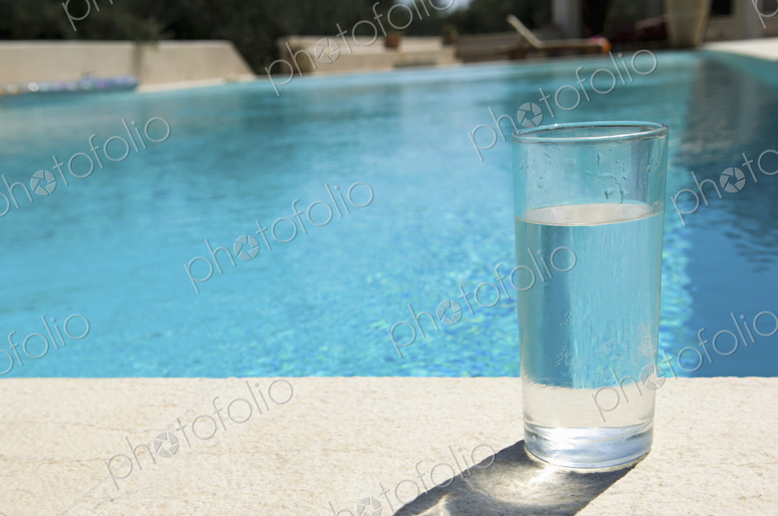 Glass of water on the side of a swimming pool