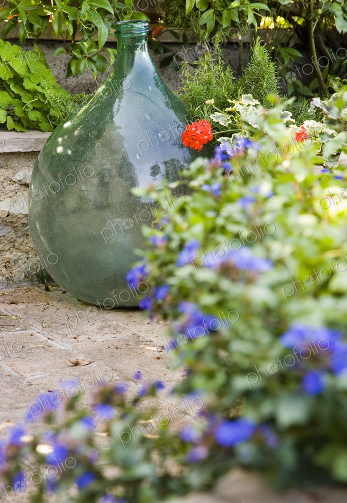 Glass vase with flower pots on terrace in garden.