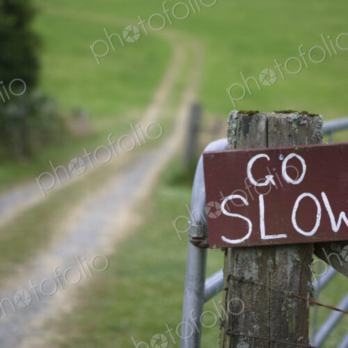Go slow sign on wooden countryside gate.